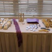 一张桌子上的照片，上面挂着紫色的特里奥塔大学毕业带, 从当地小贩那里买肥皂和咖啡豆, 以及WGS贴纸和按钮